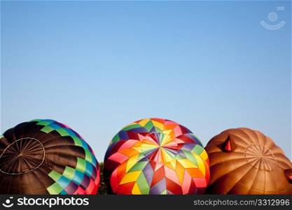 Three colorful hot air ballons being set up for a flight