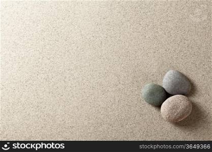 Three colorful round stones on sand background