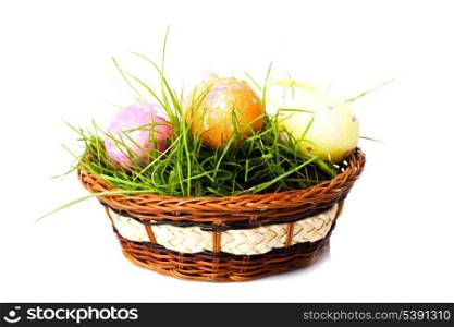 Three colorfull easter eggs on green grass in basket isolated