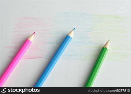 Three coloring pencils displayed on a white background that is colored in the same color as the pencils