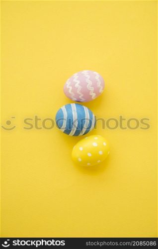 three colourful easter eggs yellow table