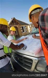 Three construction workers studying blueprint