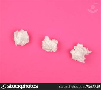 three crumpled white paper napkins on a pink background, top view