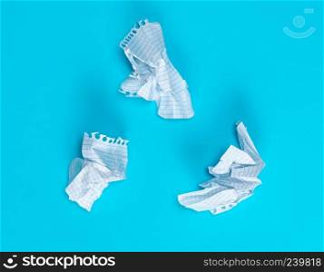 three crumpled white pieces of paper in a cell from a school notebook on a blue background