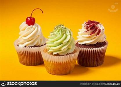 three cupcakes isolated on orange background