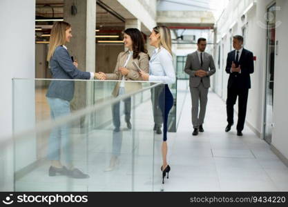 Three cute young business women having a discussion in the office hallway