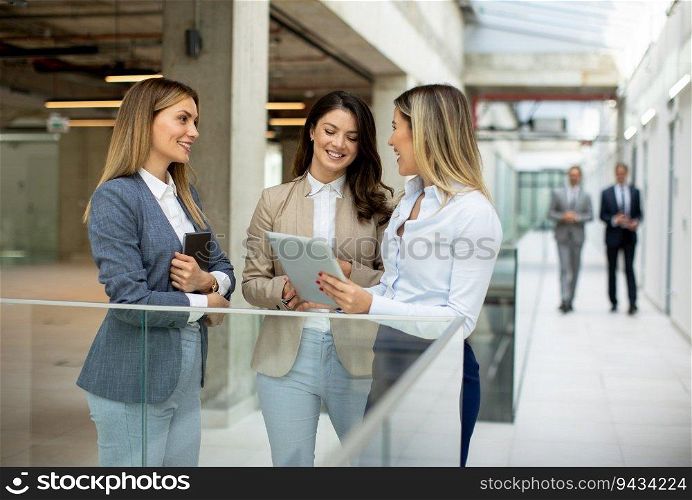 Three cute young business women having a discussion in the office hallway
