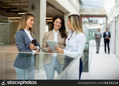 Three cute young business women having a discussion in the office hallway