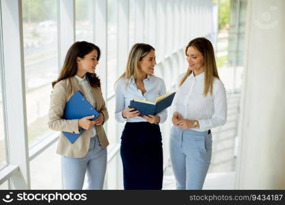 Three cute young business women having a discussion while walking in the office hallway