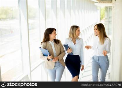 Three cute young business women walking on stairs in the office hallway