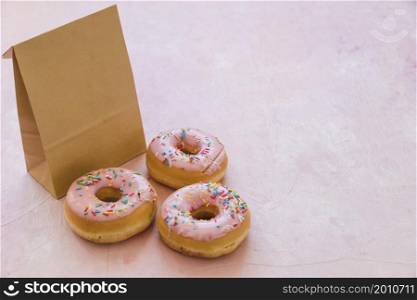 three delicious donuts with parcel pink background