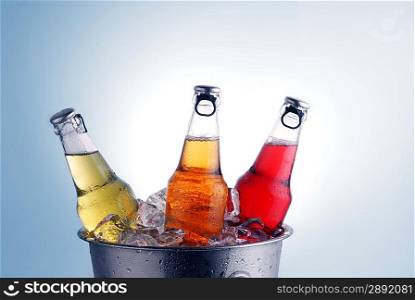 three different beer bottles in bucket of ice with condensation