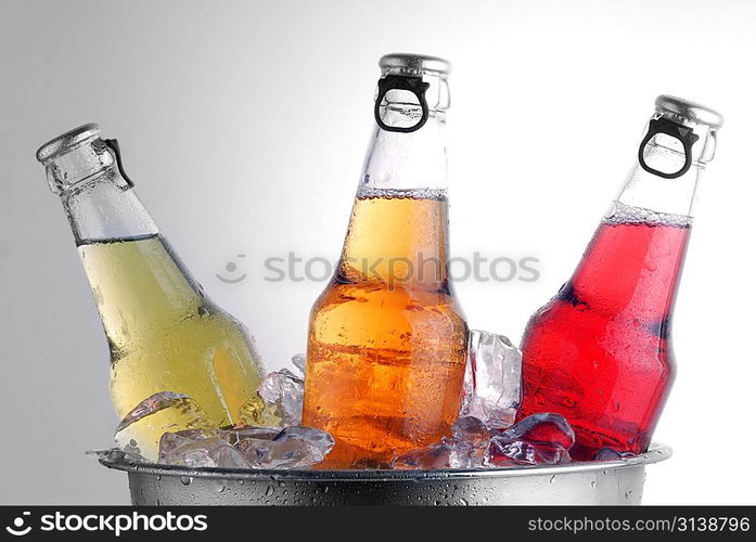 three different beer bottles in bucket of ice with condensation