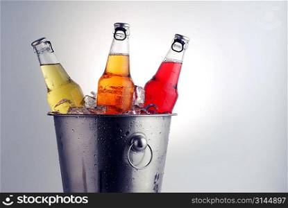 three different beer bottles in bucket of ice with condensation