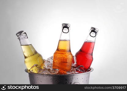 three different beer bottles in bucket of ice with condensation