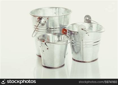 Three different in size empty buckets on a white background. Three metal buckets