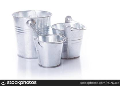 Three different in size empty buckets on a white background. Three metal buckets