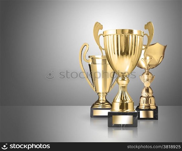 three different kind of golden trophies on gray background
