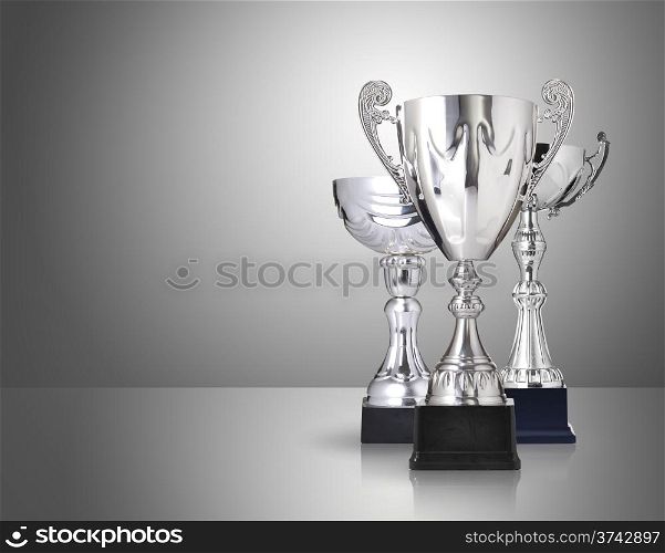 three different kind of silver trophies on gray background