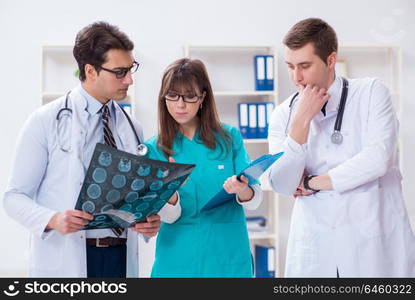 Three doctors discussing scan results of x-ray image