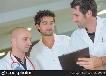 Three doctors looking at clipboard
