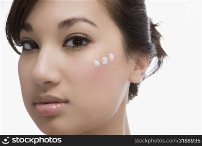 Three dots of moisturizing cream on a woman&acute;s face