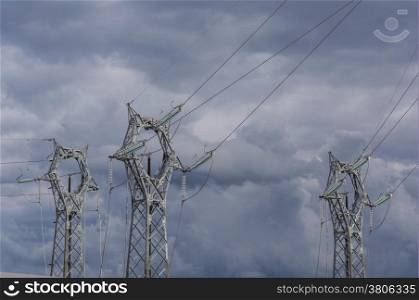 three electrical pylons on the background of a stormy sky