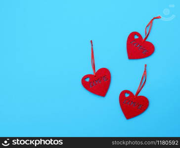 three empty felt red hearts on a blue background. Holiday celebration concept.