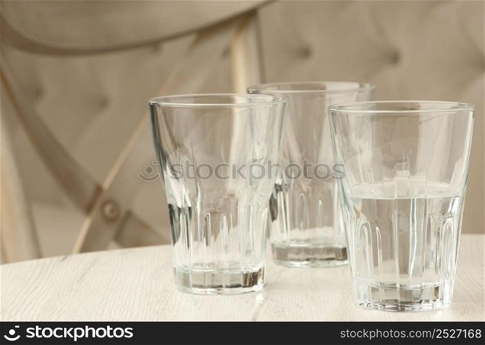 Three empty glass transparent cup on the table against the background of the chair and sofa. empty glasses on the table