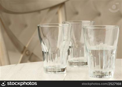 Three empty glass transparent cup on the table against the background of the chair and sofa. empty glasses on the table