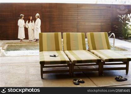 Three empty lounge chairs with three women in the background