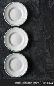 Three empty plates on the black ceramic background