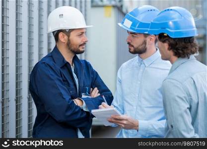three engineers checking plans with documents at construction site