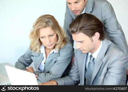 Three executives examining laptop computer