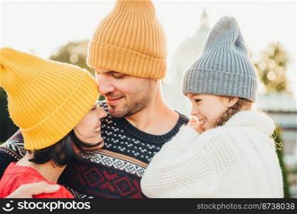 Three family members stand close to each other, look with eyes full of love and happiness, enjoy pleasant moments of being together, embrace each other. Family, happiness, relaxation concept