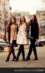 Three fashionable girlfriends walking in the city