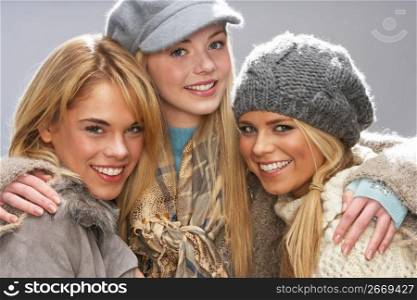 Three Fashionable Teenage Girls Wearing Cap And Knitwear In Studio