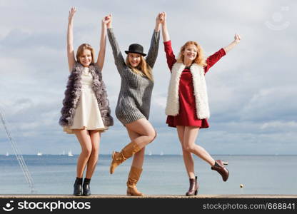 Three fashionable women having presenting pretty stylish outfits next to sea. Style, fashion, friendship concept.. Three fashionable woman against sea