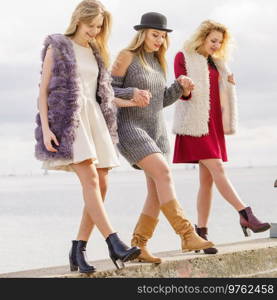 Three fashionable women having presenting pretty stylish outfits. Style, fashion, friendship concept.. Three fashionable woman outdoor