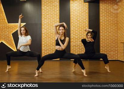 Three female contemporary dance performers poses in studio. Dancers training in class, modern elegance dancing, stretching exercise
