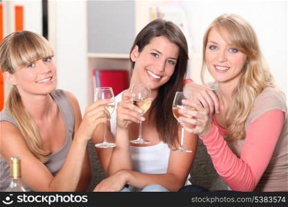 Three female friends drinking wine on sofa