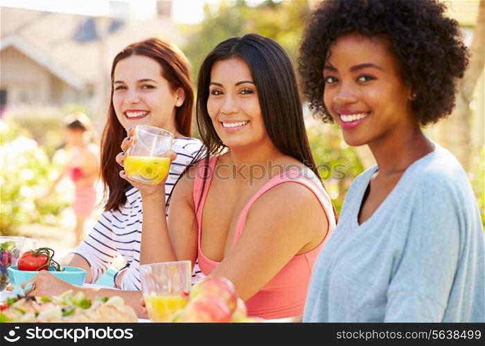 Three Female Friends Enjoying Meal At Outdoor Party