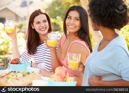 Three Female Friends Enjoying Meal At Outdoor Party