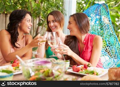 Three Female Friends Enjoying Meal Outdoors At Home