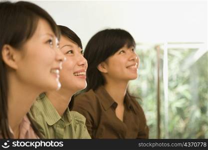 Three female office workers looking up and smiling