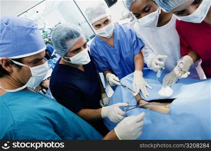 Three female surgeons and two male surgeons operating a patient