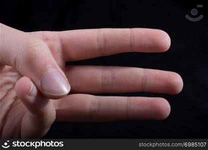 Three fingers of a child hand partly seen in black background