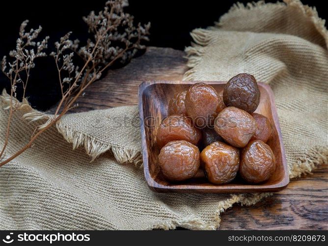 Three flavored preserved chinese plums  Preserved fruits  on wooden plate. Its flavour has sour, salty and sweet taste. Space for text, Selective Focus.