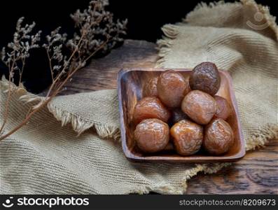 Three flavored preserved chinese plums  Preserved fruits  on wooden plate. Its flavour has sour, salty and sweet taste. Space for text, Selective Focus.