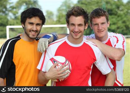 Three footballers in front of goal